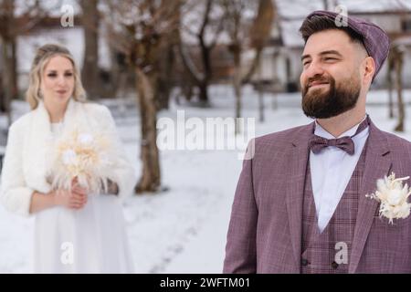 Augusta, Baviera, Germania - 19 gennaio 2024: Giovane coppia nuziale al matrimonio con abito e abito da sposa in inverno nel parco *** Junges Brautpaar bei der Hochzeit mit Anzug und Brautkleid im Winter im Park Foto Stock