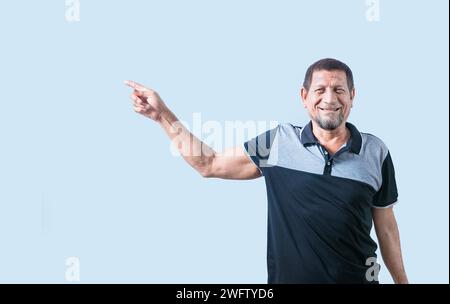 Un uomo anziano sorridente che indica il lato isolato. Uomo anziano felice che indica uno spazio pubblicitario isolato Foto Stock