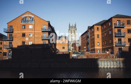 Il fiume Aire che attraversa Leeds, con blocchi di appartamenti in primo piano e Leeds Minster sullo sfondo. Preso in una giornata di sole con il cielo blu. Foto Stock