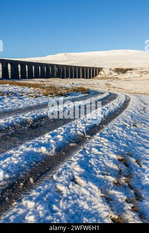 Il Viadotto Ribblehead in una giornata invernale nelle Yorkshire Dales in Inghilterra, con Whernside ricoperto di neve sullo sfondo. Preso in una giornata di sole. Foto Stock