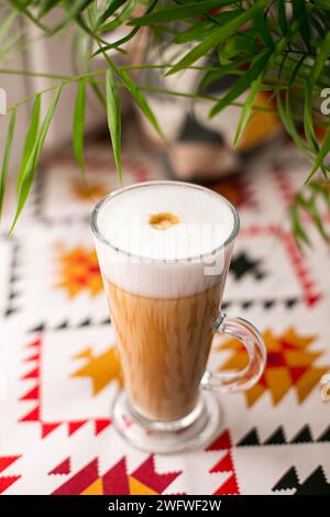 Tazza di caffè latte cappuccino e foglie verdi. primo piano Foto Stock