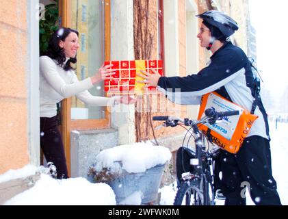 Un corriere di biciclette consegna un pacco, Monaco, Germania Foto Stock