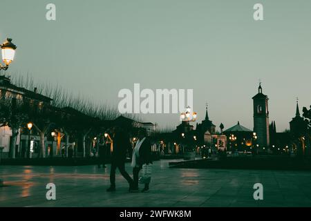 Alcala de Henares. 31 gennaio 2024 città fiabesca oscura con sagome di vecchie case, edifici con guglie contro il cielo blu notte luce di strada Foto Stock