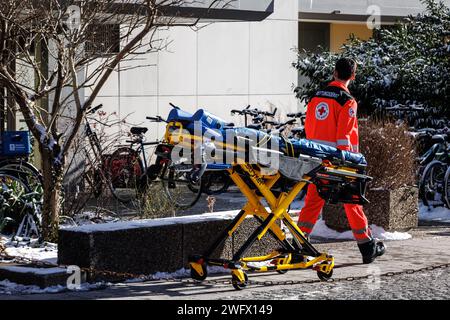 Monaco, Germania. 20 gennaio 2024. Un paramedico di emergenza del servizio ambulanza della Croce Rossa bavarese spinge una barella in un blocco di appartamenti. Crediti: Matthias Balk/dpa/Alamy Live News Foto Stock