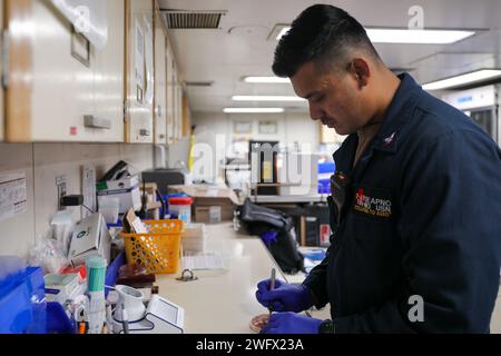 U.S. Navy Hospital Corpsman 3rd Class Benjamin Seapno, da San Diego, controlla i campioni di sangue con capsule di Petri nel laboratorio a bordo della nave ospedale USNS Mercy (T-AH 19) mentre ancorata al largo di Weno, Chuuk, Stati Federati di Micronesia, come parte della Pacific Partnership 2024-1, 18 gennaio 2024. Pacific Partnership, ora alla sua diciannovesima edizione, è la più grande missione multinazionale di assistenza umanitaria e di preparazione ai soccorsi in caso di catastrofi condotta nell'Indo-Pacifico e lavora per migliorare l'interoperabilità regionale e le capacità di risposta alle catastrofi, aumentare la stabilità della sicurezza nella regione, e per Foto Stock