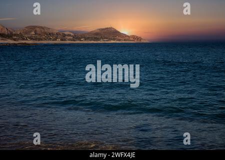 Il sole tramonta sul mare e nel deserto a Cabo San Lucas, Messico Foto Stock