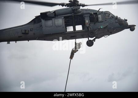 240118-N-PQ495-1320 SOUTH CHINA SEA (18 gennaio 2024) Un operatore Naval Special Warfare (NSW) respinge un MH-60S Sea Hawk, assegnato ai "Black Knights" dell'Helicopter Sea Combat Squadron (HSC) 4, durante un'evoluzione rapida della corda sul ponte di volo della portaerei classe Nimitz USS Carl Vinson (CVN 70). La Vinson, ammiraglia del Carrier Strike Group ONE, è dispiegata nell'area operativa della settima flotta degli Stati Uniti a sostegno di una Indo-Pacifico libera e aperta. Naval Special Warfare è la forza operativa marittima d'élite degli Stati Uniti, in posizione unica per estendere la portata della flotta e ottenere e mantenere la conformità Foto Stock