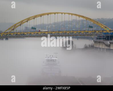 Una towboat organizza chiatte in condizioni di nebbia sul fiume Ohio a Pittsburgh, 25 gennaio 2024. Il U.S. Army Corps of Engineers Pittsburgh District gestisce 23 chiuse navigabili e dighe sui fiumi Allegheny, Monongahela e Ohio tutto l'anno, indipendentemente dalle condizioni meteorologiche, anche in condizioni di nebbia che limitano la visibilità. Molti equipaggi di barche a rimorchio continuano a lavorare sui fiumi anche nella nebbia, talvolta mettendo in scena le loro chiatte lungo varie parti lungo i corsi d'acqua di Pittsburgh mentre aspettano che la nebbia si sollevi. Indipendentemente dal tempo, le chiuse e le dighe del distretto di Pittsburgh rimangono aperte al traffico, leggi Foto Stock