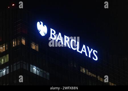 Il simbolo e il logo della Barclays Bank si illuminano di notte sul grattacielo della sede centrale della banca a Canary Wharf, Londra, Inghilterra, Regno Unito Foto Stock