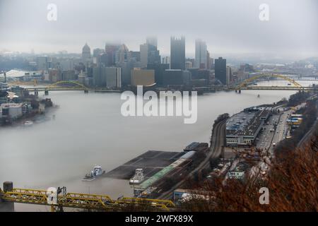 Towboats organizza chiatte in condizioni di nebbia sul fiume Ohio a Pittsburgh, 25 gennaio 2024. Il U.S. Army Corps of Engineers Pittsburgh District gestisce 23 chiuse navigabili e dighe sui fiumi Allegheny, Monongahela e Ohio tutto l'anno, indipendentemente dalle condizioni meteorologiche, anche in condizioni di nebbia che limitano la visibilità. Molti equipaggi di barche a rimorchio continuano a lavorare sui fiumi anche nella nebbia, talvolta mettendo in scena le loro chiatte lungo varie parti lungo i corsi d'acqua di Pittsburgh mentre aspettano che la nebbia si sollevi. Indipendentemente dal tempo, le chiuse e le dighe del distretto di Pittsburgh rimangono aperte al traffico, pronte Foto Stock