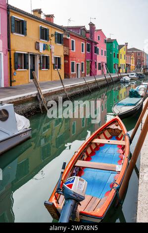 Burano, Italia - 25 febbraio 2023; case colorate lungo un canale con piccole barche a Burano, Italia Foto Stock