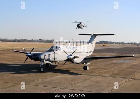 Un aereo C-12 Huron è parcheggiato sulla rampa, mentre un elicottero UH-72 Lakota taxi presso il Cairns Army Airfield il 31 gennaio 2024. Il C-12 è assegnato al distaccamento 1, compagnia B, 1st Battalion, 228th Aviation Regiment, U.S. Army Reserve, ed è di stanza a Fort Novosel, Alabama, sede del U.S. Army Aviation Center of Excellence. Foto Stock