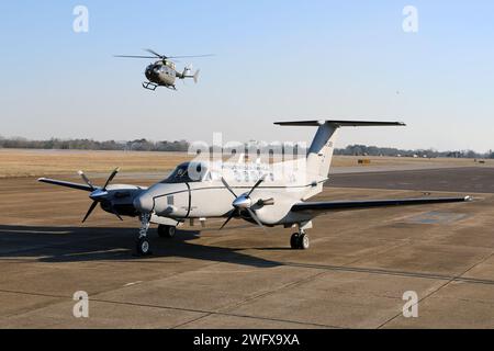 Un aereo C-12 Huron è parcheggiato sulla rampa, mentre un elicottero UH-72 Lakota taxi presso il Cairns Army Airfield il 31 gennaio 2024. Il C-12 è assegnato al distaccamento 1, compagnia B, 1st Battalion, 228th Aviation Regiment, U.S. Army Reserve, ed è di stanza a Fort Novosel, Alabama, sede del U.S. Army Aviation Center of Excellence. Foto Stock