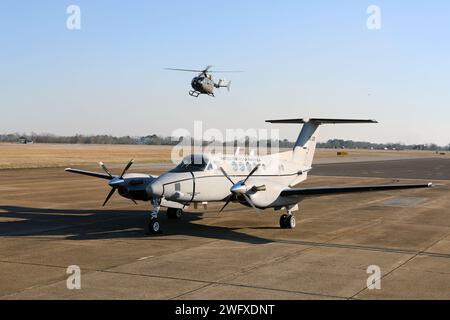 Un aereo C-12 Huron è parcheggiato sulla rampa, mentre un elicottero UH-72 Lakota taxi presso il Cairns Army Airfield il 31 gennaio 2024. Il C-12 è assegnato al distaccamento 1, compagnia B, 1st Battalion, 228th Aviation Regiment, U.S. Army Reserve, ed è di stanza a Fort Novosel, Alabama, sede del U.S. Army Aviation Center of Excellence. Foto Stock