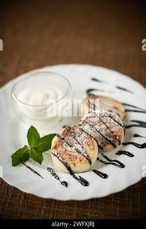 Pancake con gelato e cioccolato su un piatto bianco su un tavolo di legno da vicino Foto Stock