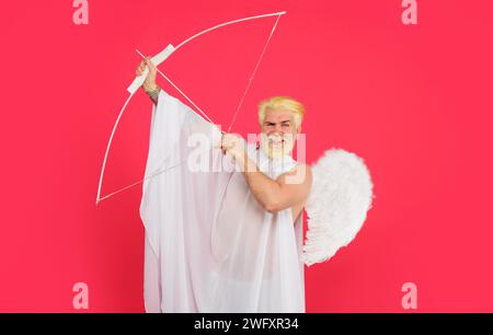 San Valentino. Amore e romanticismo. Angelo maschio sorridente che punta con arco e freccia. Valentine cupido in ali d'angelo che sparano freccia d'amore dall'arco Foto Stock