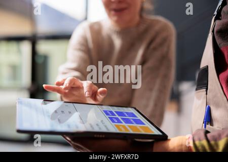 Diversi colleghi che analizzano il report di controllo della qualità delle merci su un tablet, lavorando agli ordini dei clienti in magazzino. Team di magazzino che prepara i pacchi per la consegna, controllando la detalis dei clienti Foto Stock