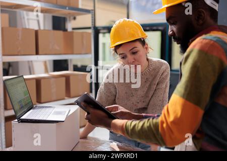 Diversi colleghi che controllano gli ordini online su tablet, analizzano i prodotti per il report dell'inventario in magazzino. Team di magazzino che lavora presso i pacchi dei clienti preparando il trasporto Foto Stock