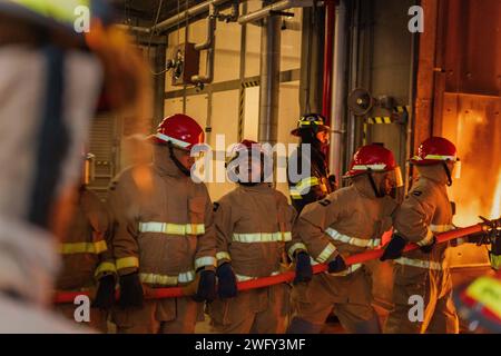 GRANDI LAGHI, il. (10 gennaio 2024) New-accession Sailors man a Firehose at Surface Warfare Engineering Schools Command Great Lakes General Ship board Firefighting (GSF) Course at Naval Station Great Lakes. Il programma di due giorni comprende lezioni in aula relative alla chimica del fuoco, classi di incendi (alfa, bravo e charlie), organizzazione di feste antincendio, estintori portatili, i dispositivi di protezione, così come i respiratori autonomi durante il primo giorno, e i laboratori di addestramento antincendio dal vivo coprono le manichette selvatiche, la manipolazione dei tubi e le procedure antincendio durante il secondo giorno. GSF Grea Foto Stock