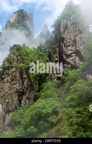 I turisti guardano il Mare Occidentale (Xihai) Grand Canyon delle Montagne Gialle di Huangshan da una scala lungo la faccia di una parete di roccia. Foto Stock