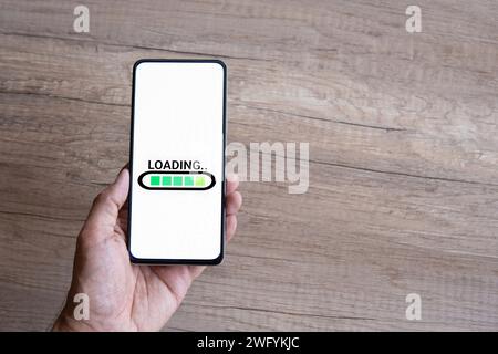 Mano che tiene lo smartphone con CARICAMENTO parole. Spazio di copia per il testo. Foto Stock
