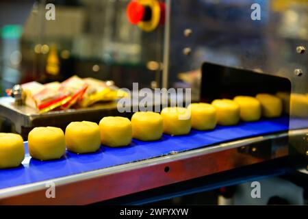 Linea di produzione automatica di snacks dorati su macchine per nastri trasportatori in fabbrica, produzione alimentare industriale. Foto Stock