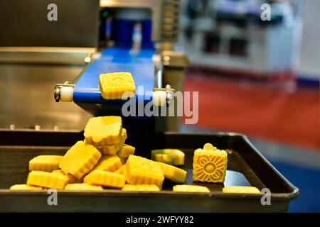 Linea di produzione automatica di snacks dorati su macchine per nastri trasportatori in fabbrica, produzione alimentare industriale. Foto Stock