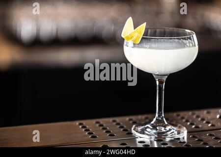 Rinfrescante cocktail francese 75 decorato con scorza di limone in un bicchiere al bar. Foto Stock