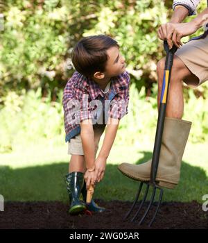 Bambino, padre e aiuto nel giardinaggio in natura utilizzando strumenti per la conservazione dell'agricoltura e l'educazione ecologica. Terra, compost e un uomo che insegna a un ragazzo Foto Stock