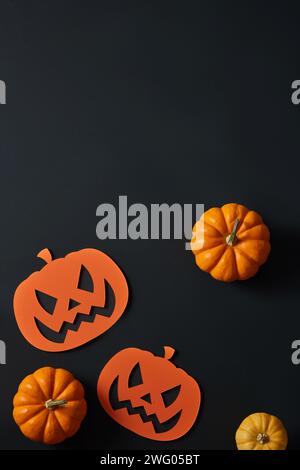 Alcune zucche e zucche di carta. Decorazioni di Halloween su sfondo nero. Spazio vuoto per la pubblicità dei prodotti Foto Stock