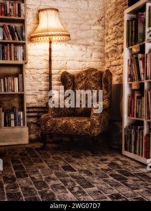 Una comoda poltrona tra i libri da lettura in una libreria di seconda mano. Foto Stock