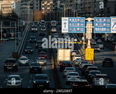 Sulle strade principali di Wuhan, un gran numero di veicoli sta guidando densamente. Il fondo stradale è illuminato dalla luce del sole Foto Stock