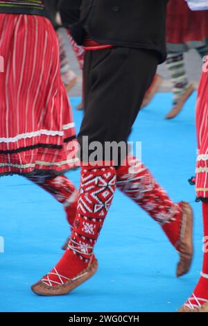Gruppo di individui in elegante abbigliamento che si scambiano sguardi in un raduno sociale: Ballerini serbi in un festival Foto Stock