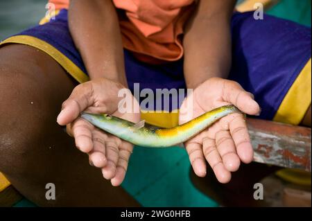 Un ragazzo mostra un pesce che ha catturato vicino a Kuta, Lombok, Indonesia. Foto Stock