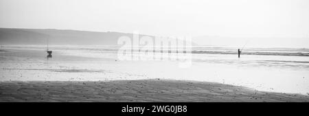 Un pescatore che pesca in mare a Sainte Anne la Palud, in Bretagna, Francia. (Bianco e nero) Foto Stock