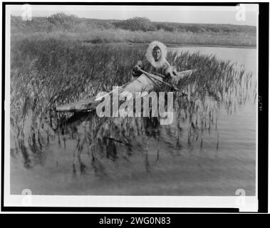 Il Muskrat-Hunter-Kotzebue, c1929. Kotzebue Man pagaia in kayak attraverso palude. Foto Stock