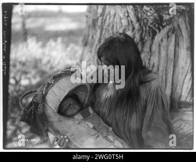 Mizheh e Babe, c1906. Donna Apache, alla base dell'albero, che tiene il bambino in culla in grembo. Foto Stock