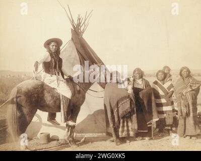 Un bel gruppo in una tenda indiana, 1891. Quattro donne Lakota in piedi, tre che tengono i neonati in culla, e un uomo Lakota a cavallo, di fronte a tipi, probabilmente nella riserva di Pine Ridge o vicino a essa. Foto Stock