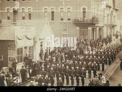 Deadwood Grand Lodge IOOF of Dakotas Street Parade, 21 maggio 1890, 1890. Gruppo di uomini in uniforme in sfilata di strada; passanti sul lato. Foto Stock