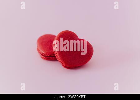 Macaron francesi a forma di cuore rosa su sfondo pastello rosa. Concetto per San Valentino. Posiziona per testo. Foto Stock