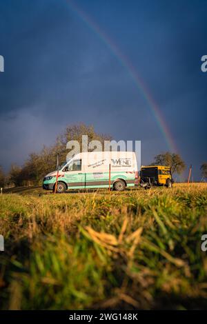 Un furgone per consegne guida su una strada di campagna con un arcobaleno sullo sfondo, costruzione in vetroresina, Nagold, Foresta Nera, Germania Foto Stock