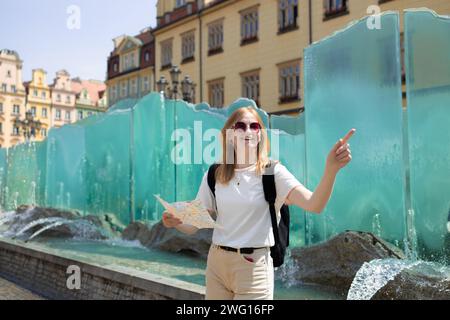 Vista fantastica delle antiche case in una giornata di sole. Donna con mappa della città e smartphone. Scena meravigliosa e pittoresca. Posizione famosa Piazza del mercato Foto Stock