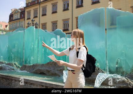 Vista fantastica delle antiche case in una giornata di sole. Donna con mappa della città e smartphone. Scena meravigliosa e pittoresca. Posizione famosa Piazza del mercato Foto Stock