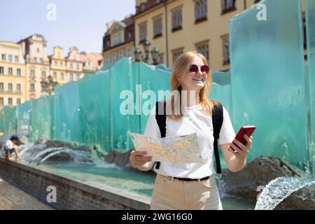 Vista fantastica delle antiche case in una giornata di sole. Donna con mappa della città e smartphone. Scena meravigliosa e pittoresca. Posizione famosa Piazza del mercato Foto Stock