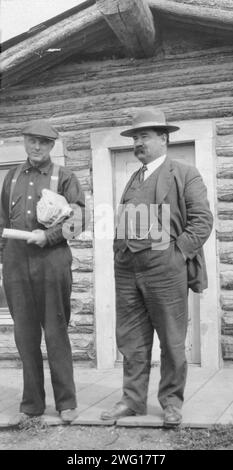 Dan Cadzow, tra il c1900 e il 1916. Due uomini in piedi di fronte alla costruzione di tronchi. Foto Stock