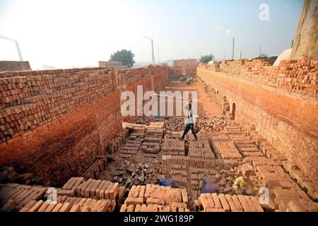 I lavoratori lavorano in un brickyard il 2 febbraio 2024 a Dacca, Bangladesh. Il Bangladesh attraversa una rapida urbanizzazione. La rapida urbanizzazione genera una domanda massiccia di mattoni, in quanto è uno degli ingredienti chiave per costruire strutture in cemento. Per rispondere a questa crescente esigenza, il numero dei campi di produzione di mattoni è aumentato a un ritmo allarmante in Bangladesh. La maggior parte di essi avviene in terreni agricoli che causano una riduzione della produzione agricola, e la combustione del carbone provoca enormi emissioni di CO2 di carbonio-di-ossido, che è principalmente responsabile del cambiamento climatico. Dhaka Dhaka Distretto di Bangla Foto Stock