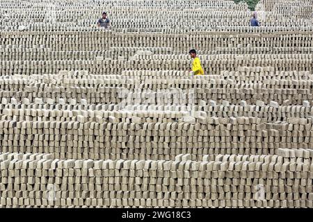 I lavoratori lavorano in un brickyard il 2 febbraio 2024 a Dacca, Bangladesh. Il Bangladesh attraversa una rapida urbanizzazione. La rapida urbanizzazione genera una domanda massiccia di mattoni, in quanto è uno degli ingredienti chiave per costruire strutture in cemento. Per rispondere a questa crescente esigenza, il numero dei campi di produzione di mattoni è aumentato a un ritmo allarmante in Bangladesh. La maggior parte di essi avviene in terreni agricoli che causano una riduzione della produzione agricola, e la combustione del carbone provoca enormi emissioni di CO2 di carbonio-di-ossido, che è principalmente responsabile del cambiamento climatico. Dhaka Dhaka Distretto di Bangla Foto Stock