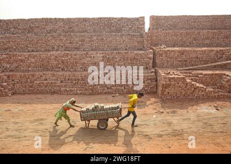 I lavoratori lavorano in un brickyard il 2 febbraio 2024 a Dacca, Bangladesh. Il Bangladesh attraversa una rapida urbanizzazione. La rapida urbanizzazione genera una domanda massiccia di mattoni, in quanto è uno degli ingredienti chiave per costruire strutture in cemento. Per rispondere a questa crescente esigenza, il numero dei campi di produzione di mattoni è aumentato a un ritmo allarmante in Bangladesh. La maggior parte di essi avviene in terreni agricoli che causano una riduzione della produzione agricola, e la combustione del carbone provoca enormi emissioni di CO2 di carbonio-di-ossido, che è principalmente responsabile del cambiamento climatico. Dhaka Dhaka Distretto di Bangla Foto Stock