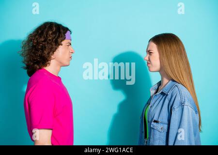 Foto del profilo laterale di un fidanzato di coppia furioso che guarda la sua ragazza che si agita isolata su sfondo color acquamarina Foto Stock