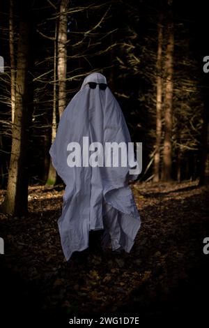 Un bambino in un foglio bianco finge di essere un fantasma ad Halloween Foto Stock